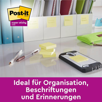 Pe un birou se află Post-it® Super Sticky 100% Notes de reciclare de la 3M Deutschland GmbH (76x76mm, 70 foi/bloc), cu text german care evidențiază organizarea, amintirile și etichetarea; dosare etichetate și un smartphone în fundal.