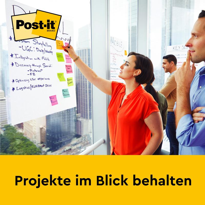 O femeie scrie pe un Post-it® Super Sticky autoadeziv Meeting Chart (58,4 x 50,8 cm, 20 de foi) de la 3M Deutschland GmbH, care este montat pe un perete de birou. Două persoane stau alături. Jos scrie: „Păstrați proiectele în vedere.”
