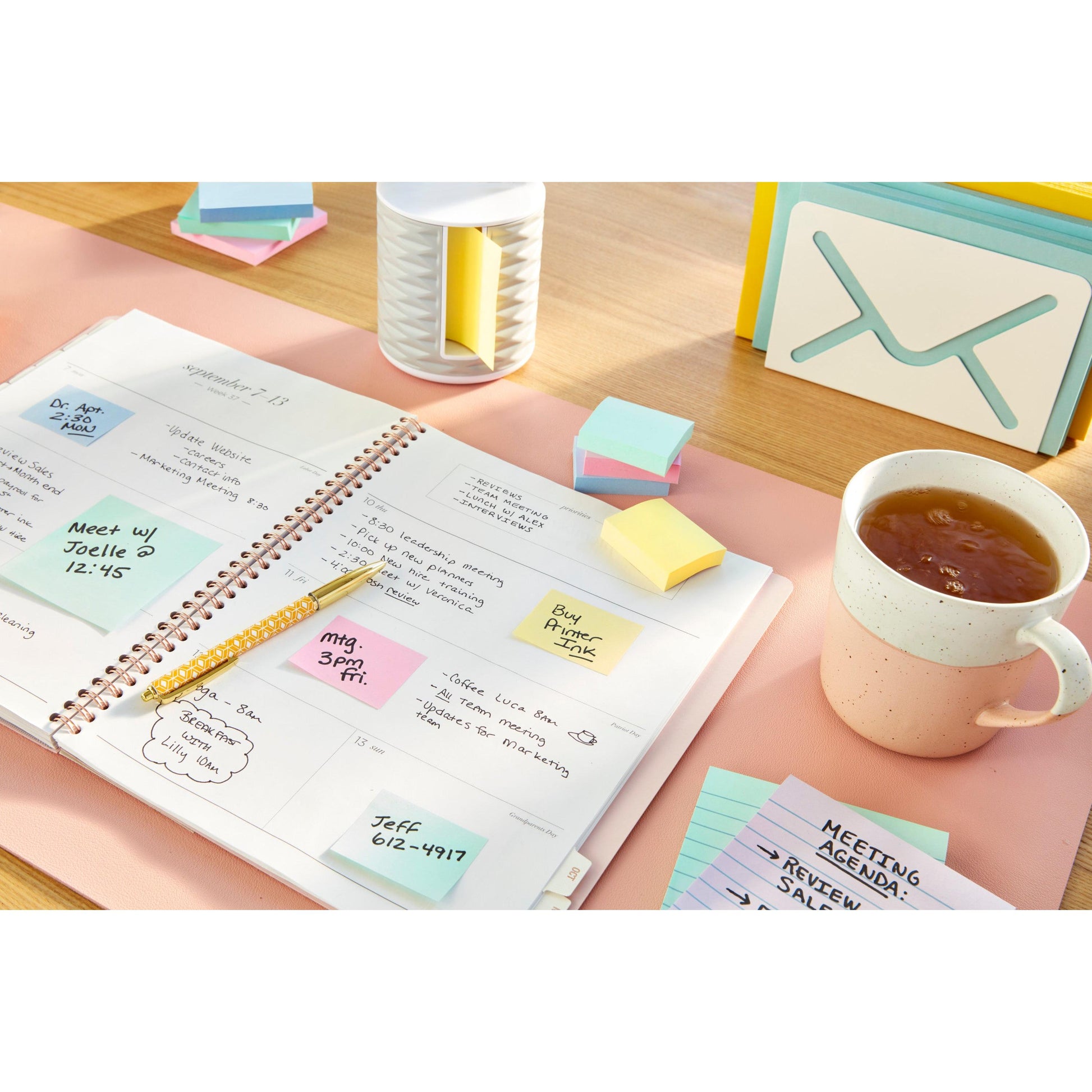 Ein offener Planer mit handschriftlichen Notizen liegt auf einem Schreibtisch mit einem Stift, Karteikarten mit der Aufschrift "Meeting Agenda", einem kuvertförmigen Organizer und einer Packung 3M Post-it® Recycling Z-Notes (76x76 mm, 100% PEFC) der 3M Deutschland GmbH.