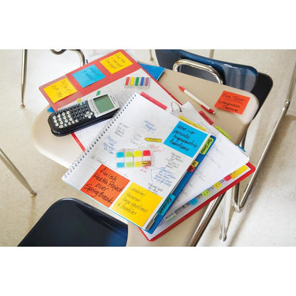 Pe o bancă de clasă sunt caiete, un planificator cu 3M Post-it® Index Strong Ablagetabs (Mini, galben, roșu, albastru & verde), calculator, pixuri, markere & mape; scaunele goale îl înconjoară și filele ajută la organizarea documentelor.