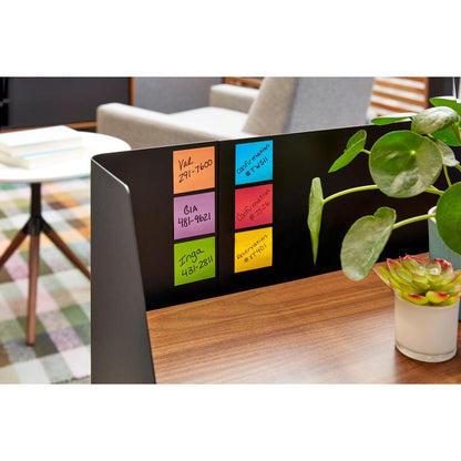 Un separator metalic negru pe o masă de lemn arată șase pachete de post-it-uri 3M Deutschland GmbH, Galben, 76x76mm, 90 foi/bloc, certificat PEFC. Plante verzi în ghiveci decorează biroul, în fundal sunt cărți și un scaun.