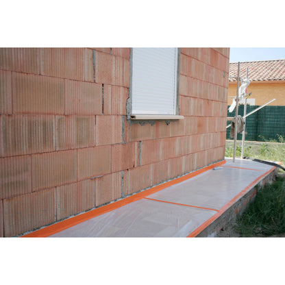 Eine teilweise gemauerte Wand mit einem unfertigen Fenster und einem Rollladen. Der Boden ist mit Kunststoffplatten bedeckt, die mit 3M Deutschland GmbH Scotch® High Visibility Klebeband, orange, 25 m x 48 mm, gesichert sind. Im Hintergrund sind Gras und ein weiteres Gebäude zu sehen.