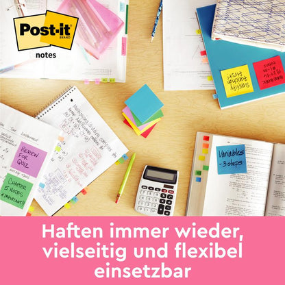 Un birou cu caiete deschise, un calculator, pixuri și notițe Post-it® colorate de la 3M Deutschland GmbH din Joyful Collection (76mm x 63,5mm, 75 foi/bloc, 2 blocuri/pachet), care sunt împrăștiate. "Aderă mereu, versatil și flexibil de utilizat.