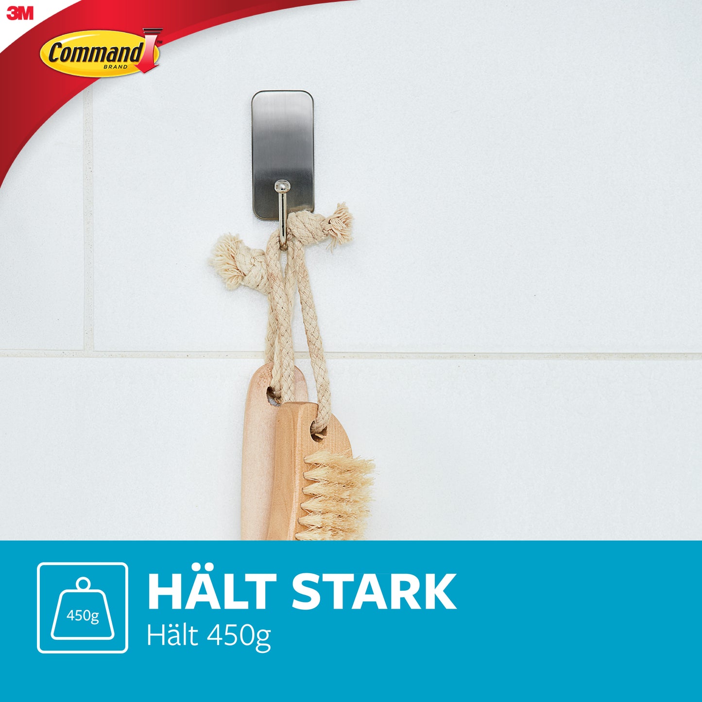 Ein Command™ Metall-Haken Bad, schmal, Satin Nickel von 3M Deutschland GmbH ist an einer weißen Fliese angebracht und hält ein Seil mit zwei Holzbürsten. Text: "HÄLT STARK. Hält 450g." Ideal für Badezimmer-Aufbewahrung ohne Bohren.