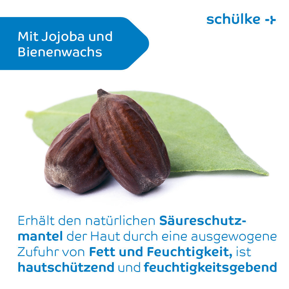 Abgebildet ist eine Nahaufnahme von zwei braunen Samen, die auf einem grünen Blatt ruhen. Im Hintergrund ist eine blaue Form mit dem Text „Mit Jojoba und Bienenwachs“ zu sehen. Darunter erklärt ein deutscher Text die hautschützenden und feuchtigkeitsspendenden Vorteile dieser Inhaltsstoffe in der Schülke esemtan® Hautlotion von Schülke & Mayr GmbH.